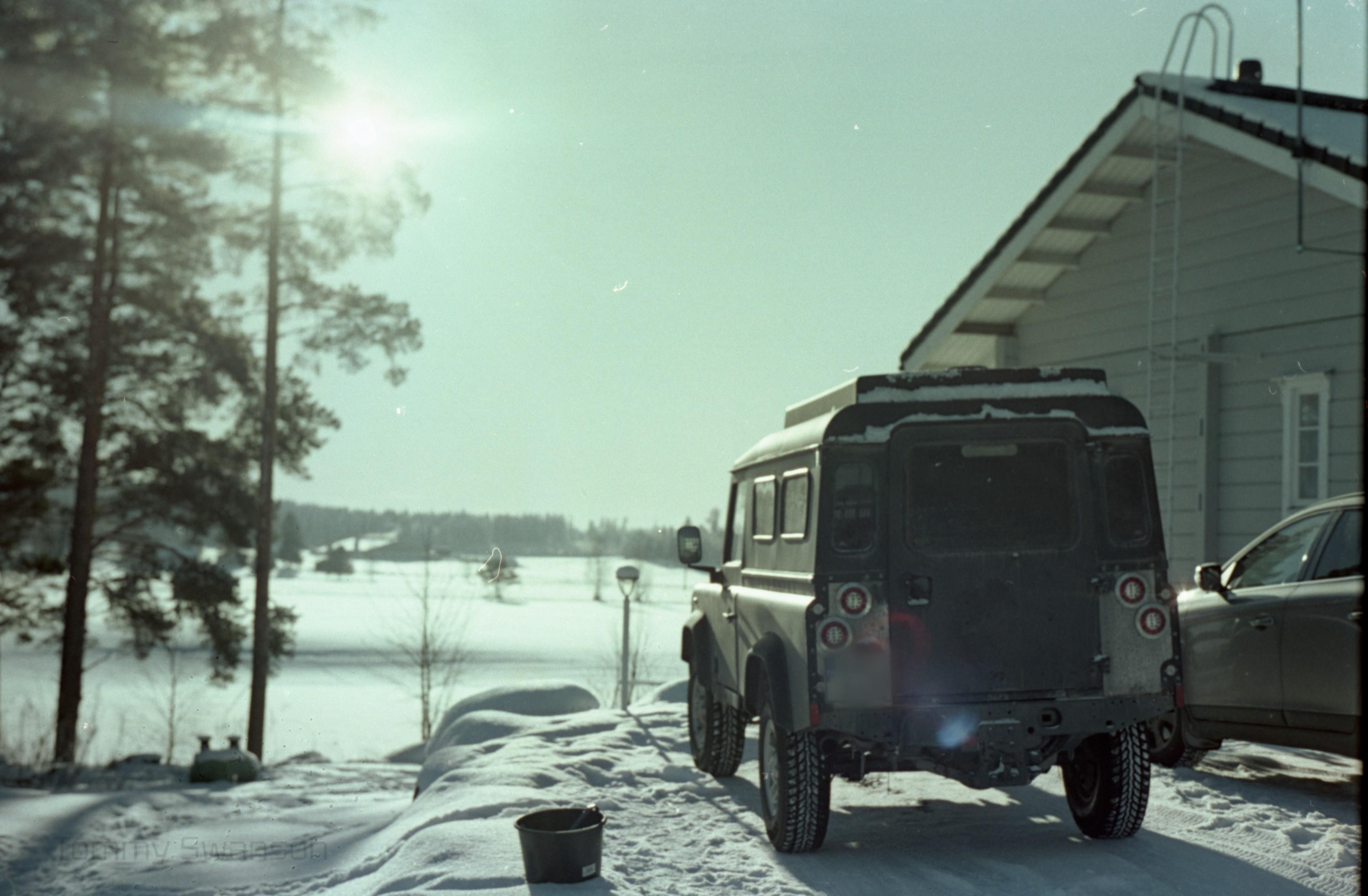Land Rover parked in front of a house facing a sunny field