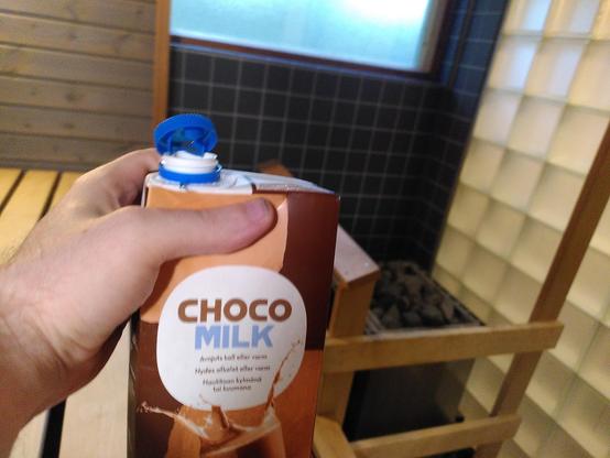 holding up a 1L carton of chocolate milk in a sauna